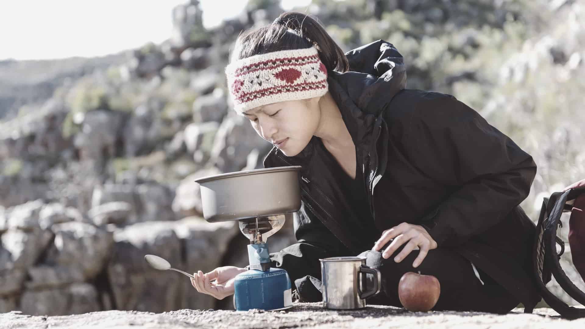 women backpacker cooking on backpacking stove